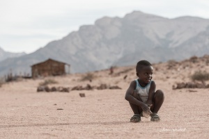 Damaraland boy with village background. Namibia Photo Tours